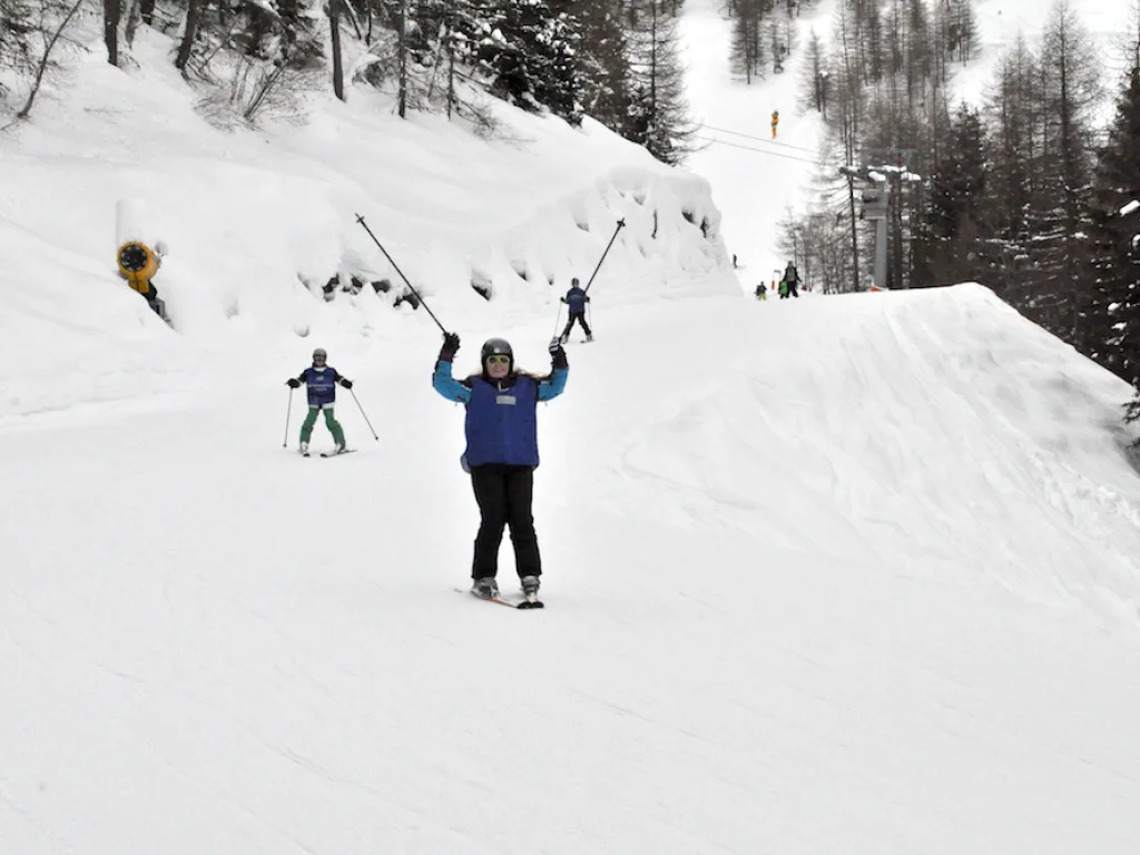 Person mit erhobenen Armen auf der Piste, dahinter weitere Fahrende.